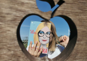 Praca konkursowa Julii Kowalewskiej okładka książki z częścią twarzy w wykrojonym jabłku